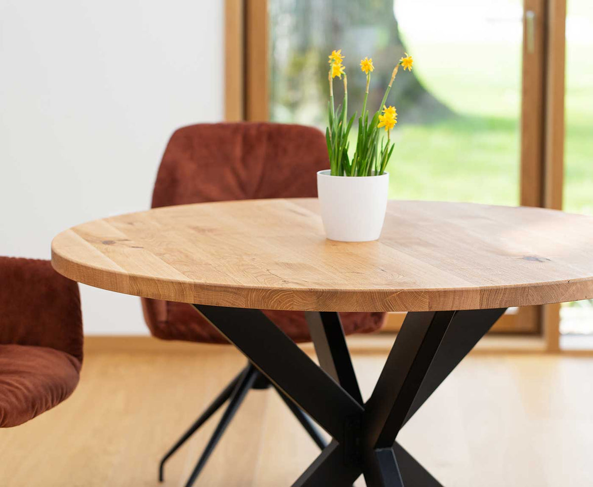 Nahaufnahme der runden Tischplatte aus Holz mit Deko und schwarzem Gestell