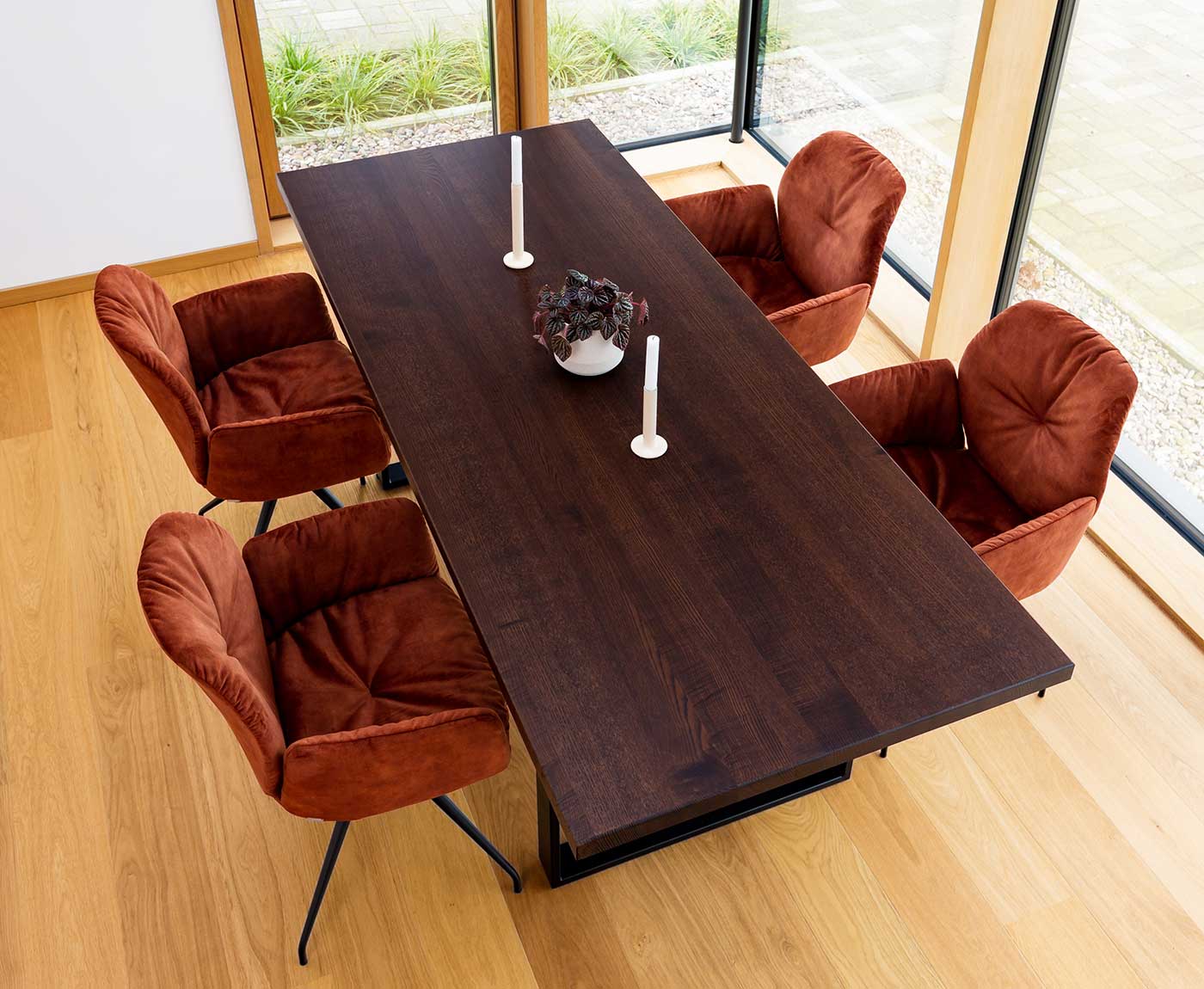 Tischplatte aus Holz in Walnuss mit Deko und vier roten Stühlen.