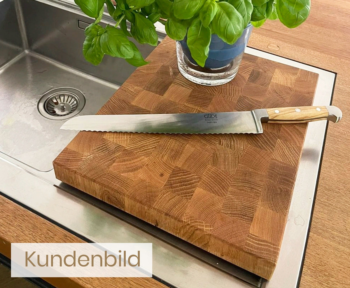 Kundenbild von Stirnholz Schneidebrett aus Eiche mit Brotmesser und Basilikumpflanze.