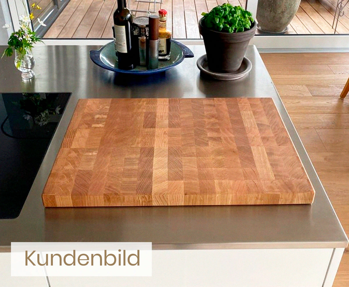 Kundenbild von Stirnholz Schneidebrett Eiche auf Edelstahl Arbeitsplatte und Basilikumpflanze.