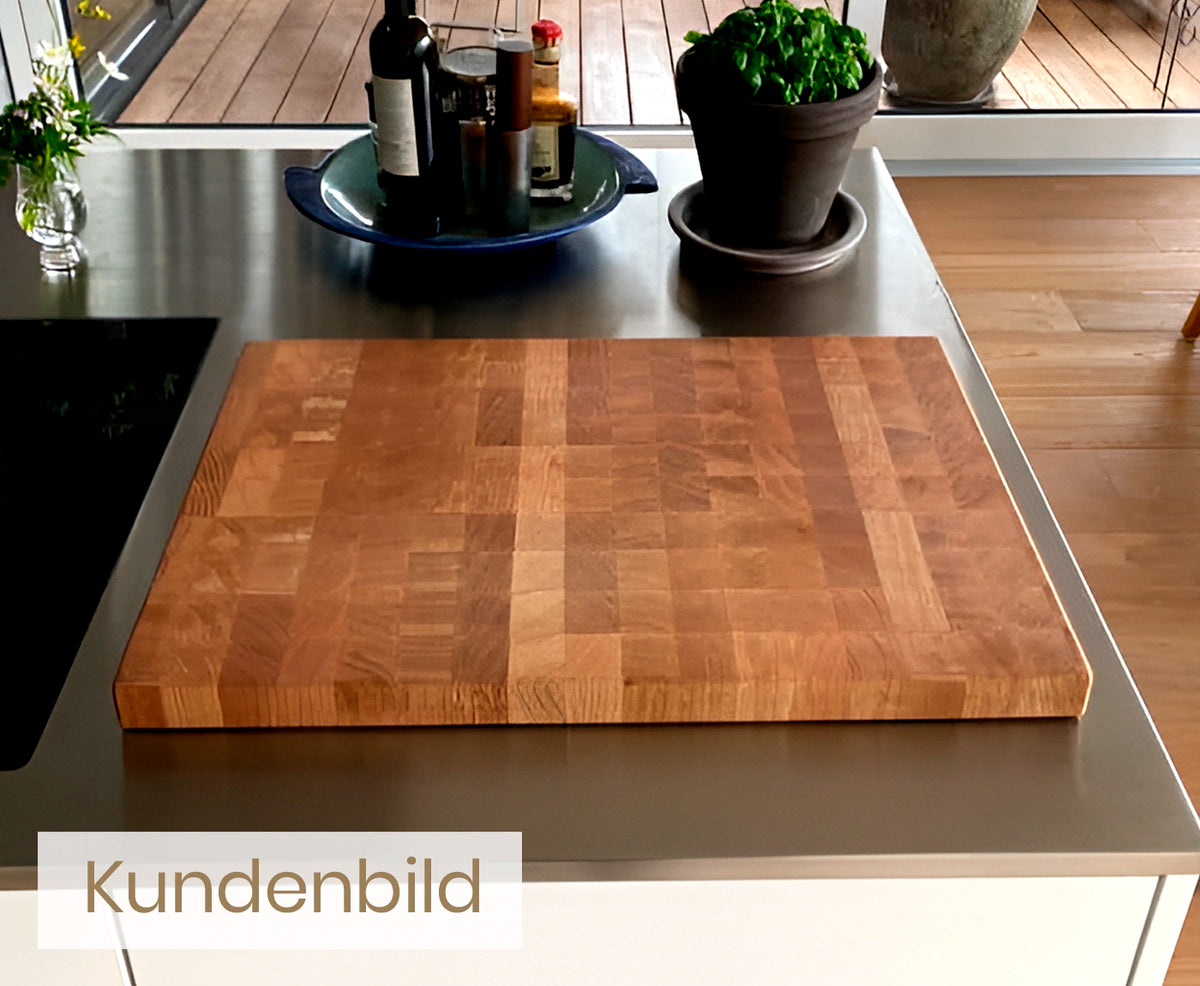 Kundenbild eines Stirnholz Schneidebretts mit Pflanze und Küchenutensilien im Hintergrund.