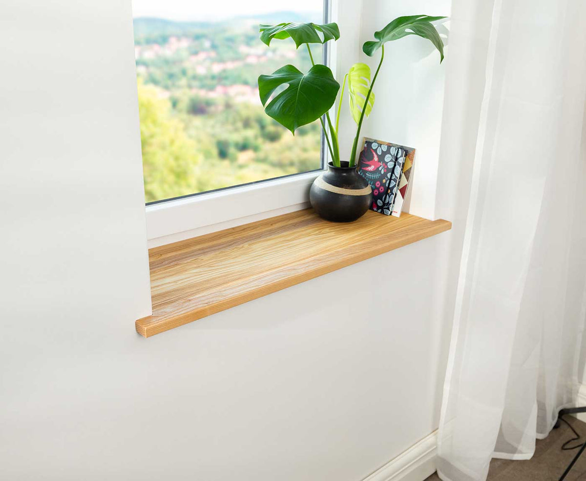 Seitliche Aufnahme einer Fensterbank innen in Esche Premium im Fensterrahmen.