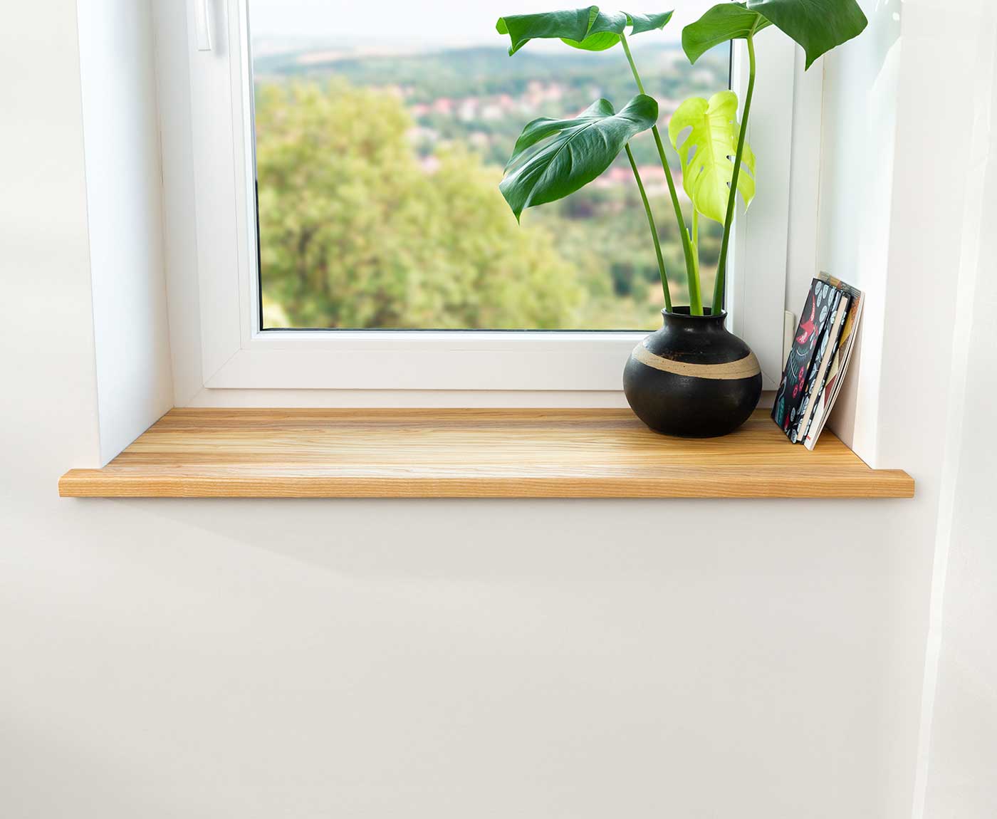 Fensterbank innen in Esche Premium im Fensterrahmen mit Deko und Zeitschriften.