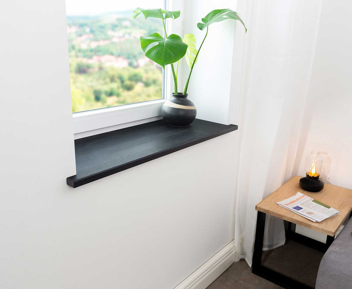 Seitliche Aufnahme einer Fensterbank innen in Esche Schwarz, sowie Couchtisch mit Deko.