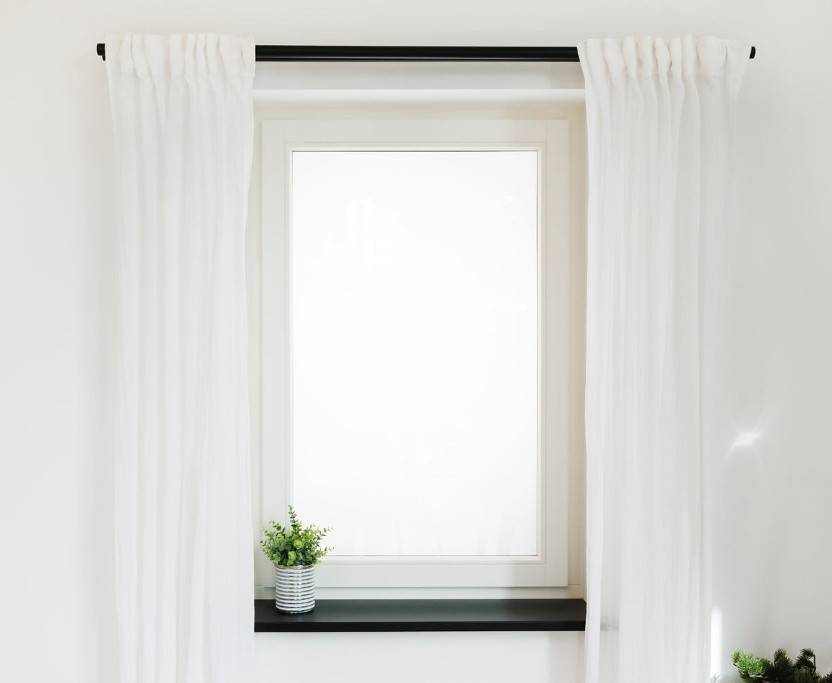 Fenster mit schwarzer Gardinenstange und Fensterbank mit Pflanzen, sowie weißen Gardinen