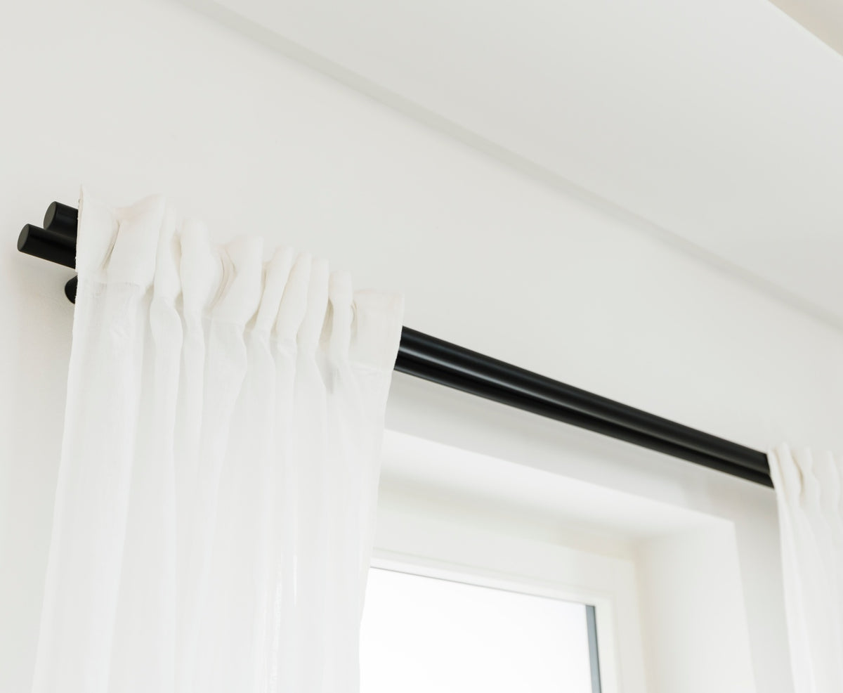 Sicht von unten auf schwarze Gardinenstange doppelt, mit weißer Gardine