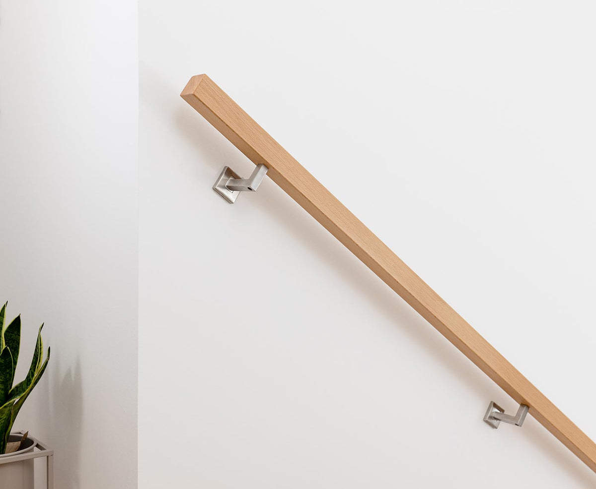 Quadratischer Treppenhandlauf aus Buche mit modernen Edelstahl-Handlaufhaltern montiert.