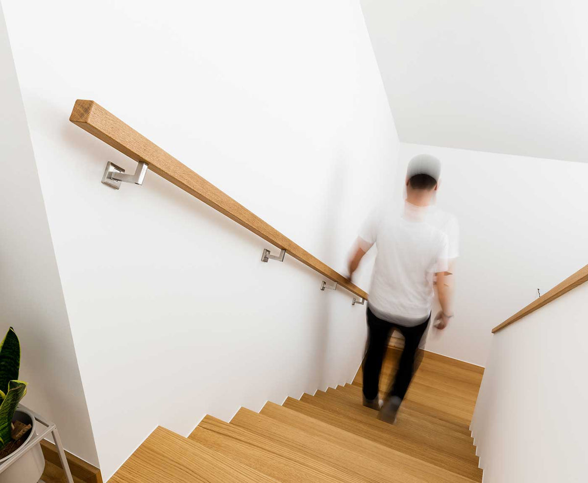 Quadratischer Handlauf aus Eiche mit Person auf der Treppe.