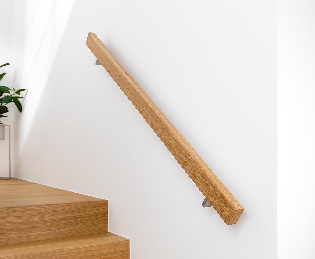 Rechteckiger Handlauf Eiche mit Edelstahl-Halterungen an weißer Wand befestigt.