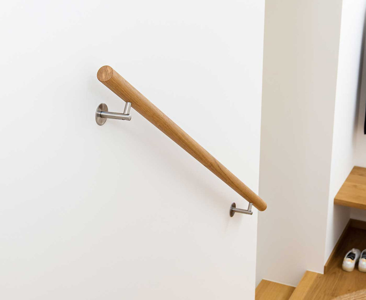 Holzhandlauf Eiche als Treppengeländer an weißer Wand montiert.