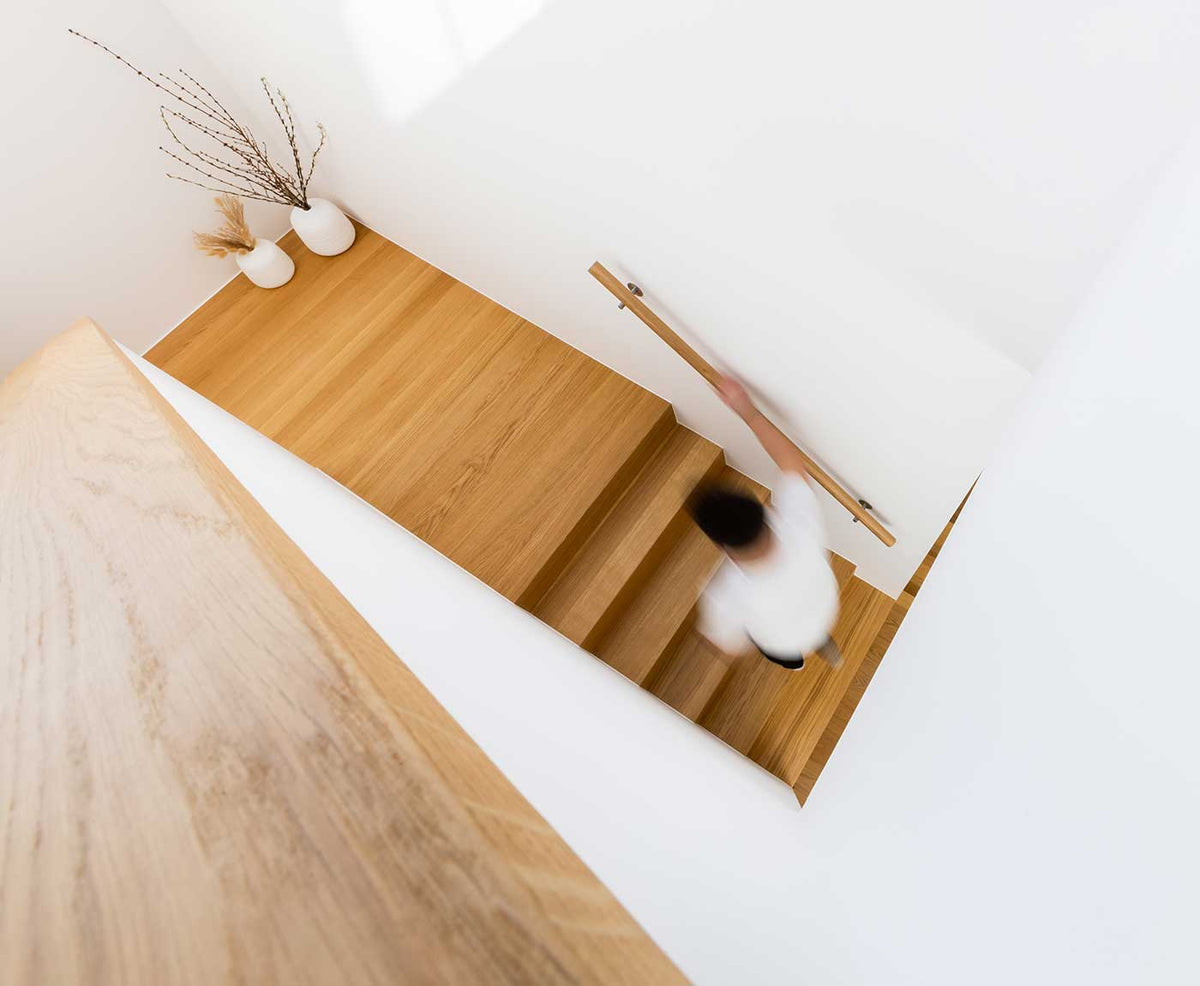 Treppenaufgang mit Person und Handlauf aus Holz von oben