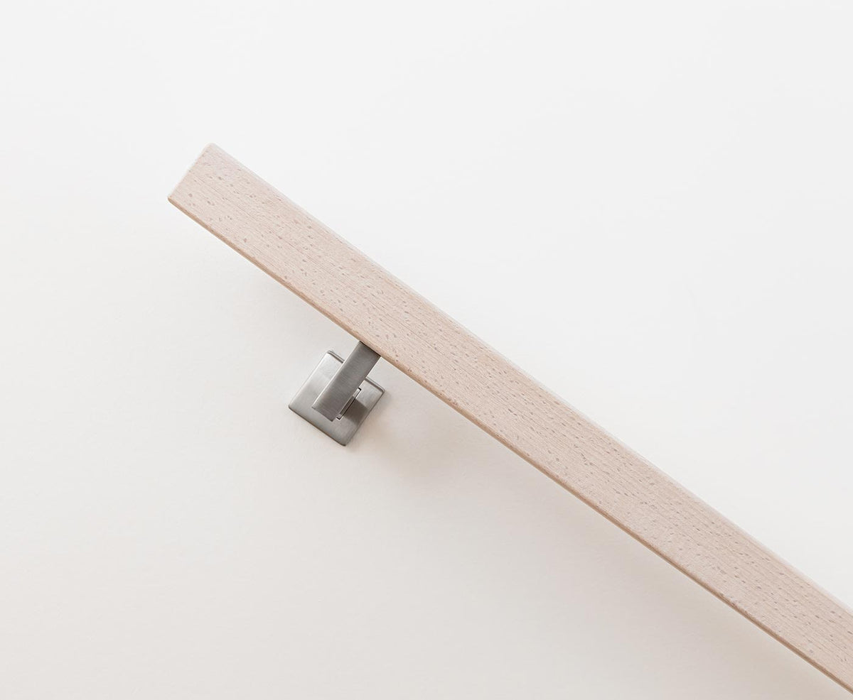 Seitansicht eines quadratischen Handlaufs aus Holz im Farbton Weiß leicht deckend, mit modernem Halter.
