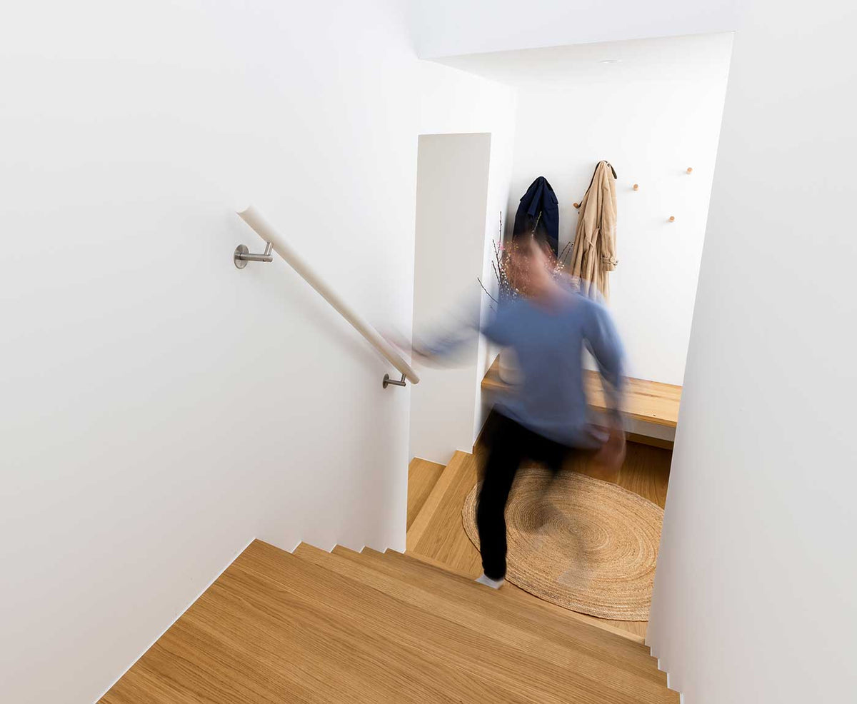 Person bei der Nutzung der Holztreppe und des weißen Handlaufs.
