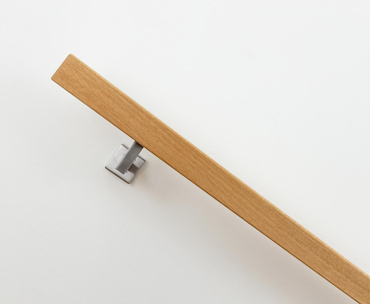 Rechteckiger Holz Handlauf aus Eiche von der Seite, mit modernem Edelstahlhalter an weißer Wand montiert.