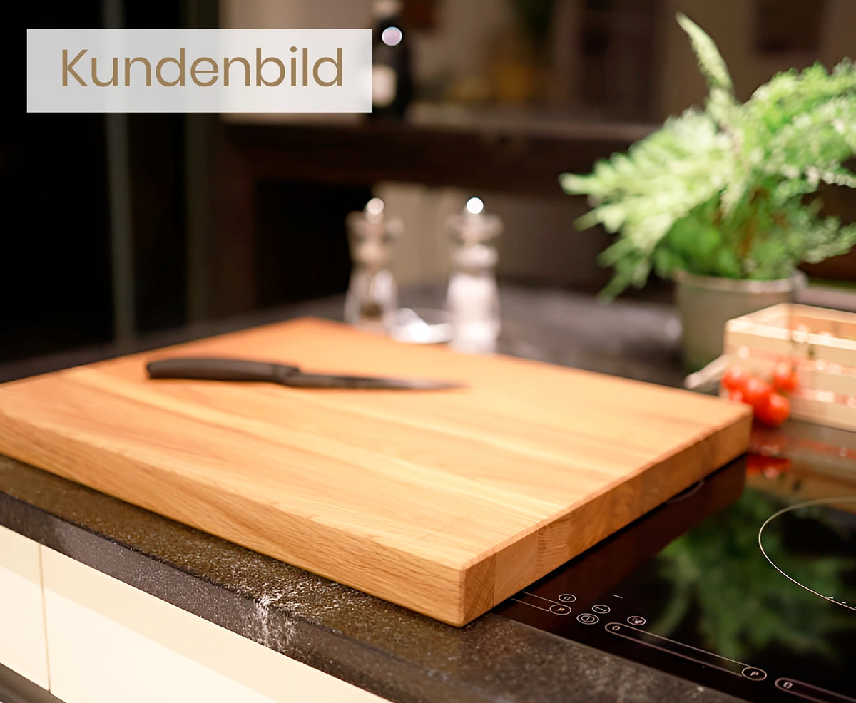 Seitliche Aufnahme eines Holz Küchenbretts aus Eiche mit Messer, auf Kücheninsel.