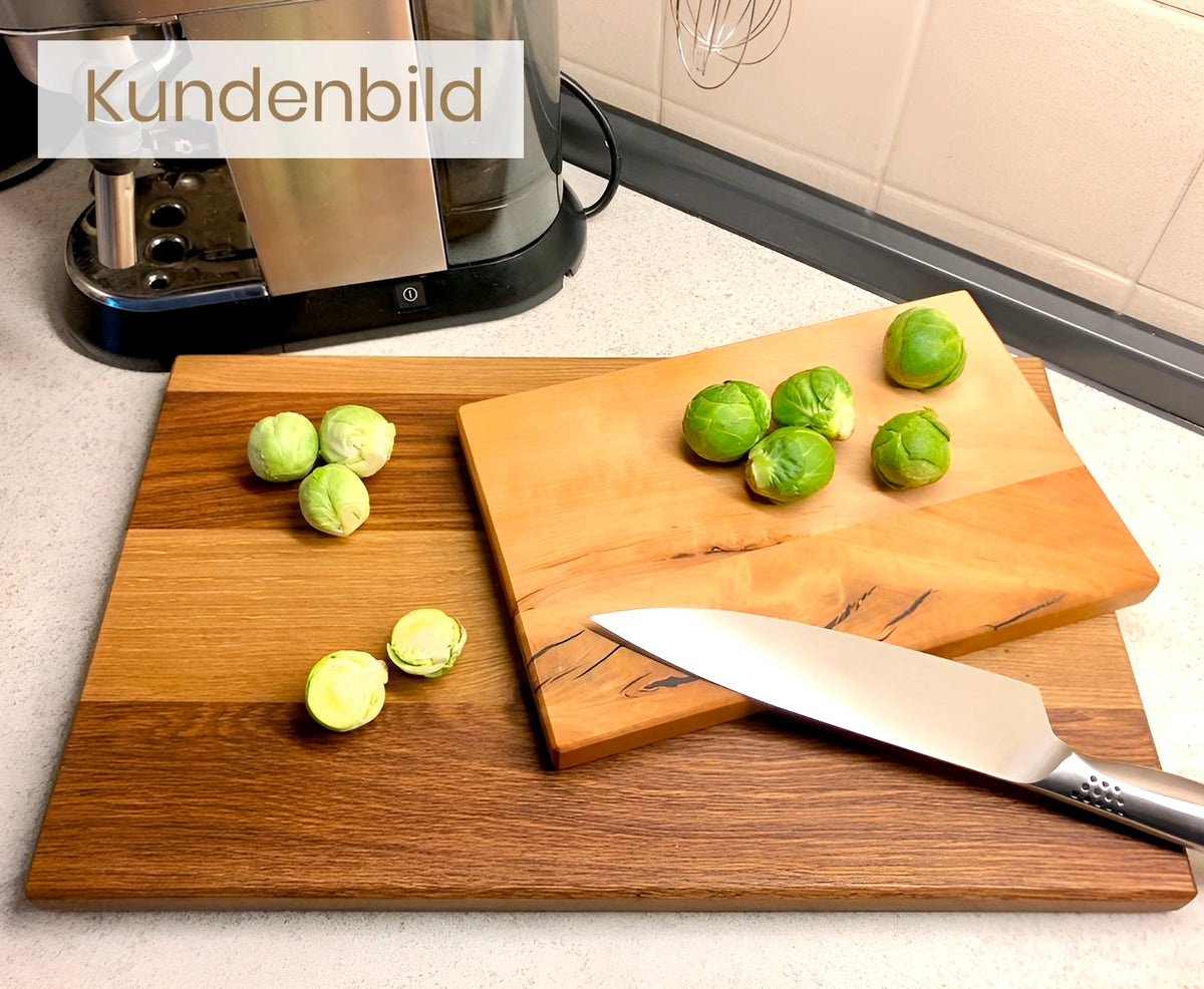 Kundenbild von großem und kleinen Küchenbrett Holz mit Rosenkohl und Messer auf heller Arbeitsplatte.