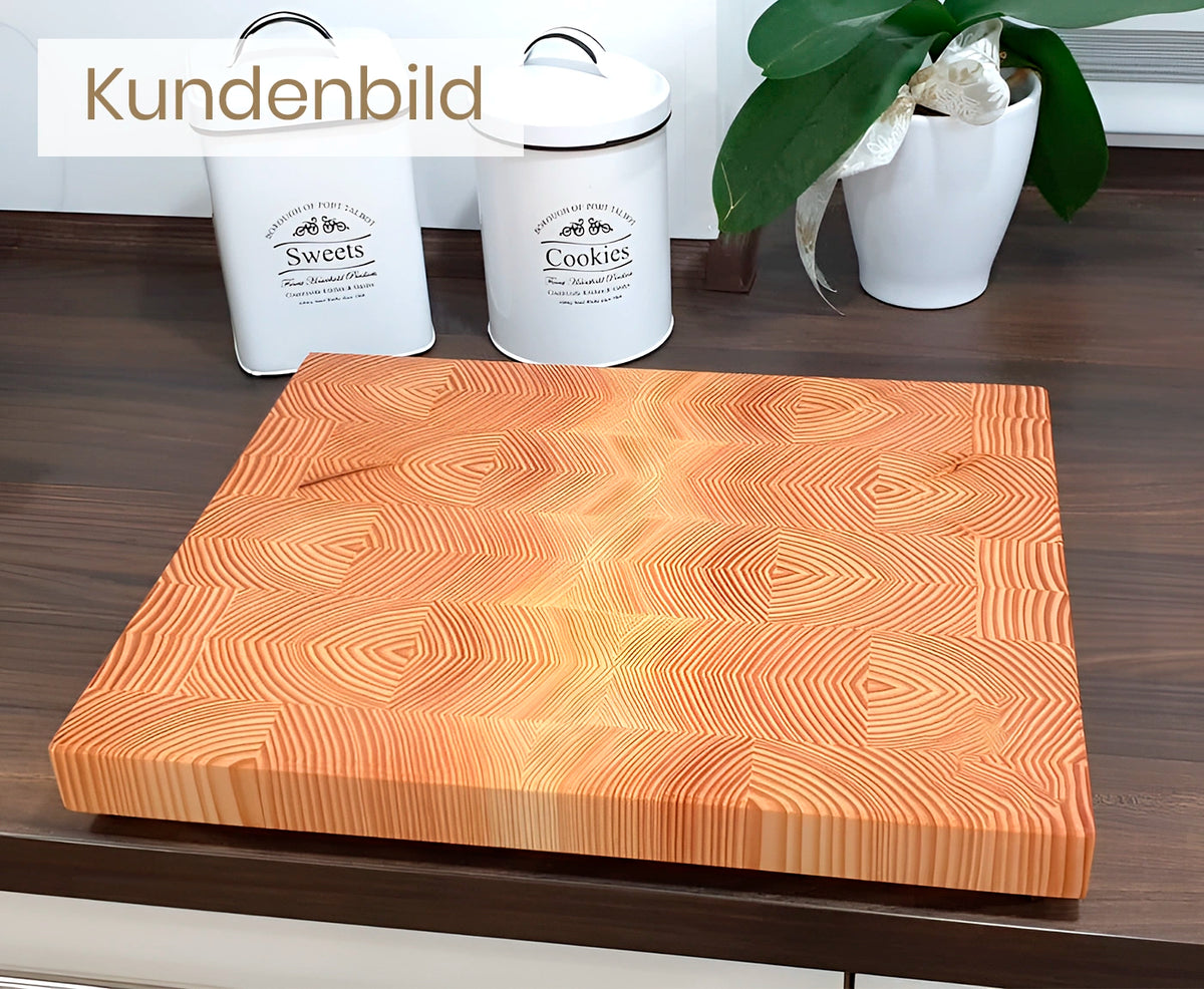 Kundenbild des Stirnholz Schneidebretts aus Lärche mit weißen Dosen und Pflanze im Hintergrund.